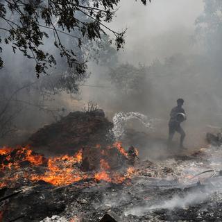 Un homme essaye d'éteindre un incendie pendant une canicule sans précédent en Inde. [Keystone/EPA - Rajat Gupta]