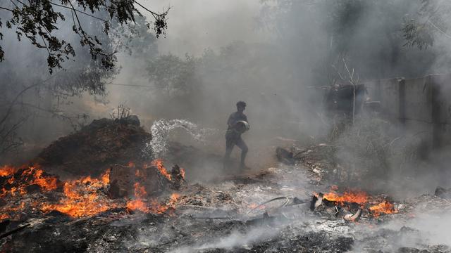 Un homme essaye d'éteindre un incendie pendant une canicule sans précédent en Inde. [Keystone/EPA - Rajat Gupta]