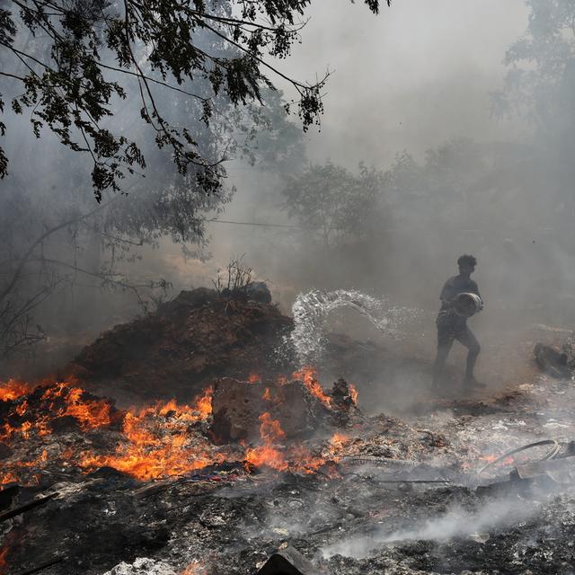 Un homme essaye d'éteindre un incendie pendant une canicule sans précédent en Inde. [Keystone/EPA - Rajat Gupta]