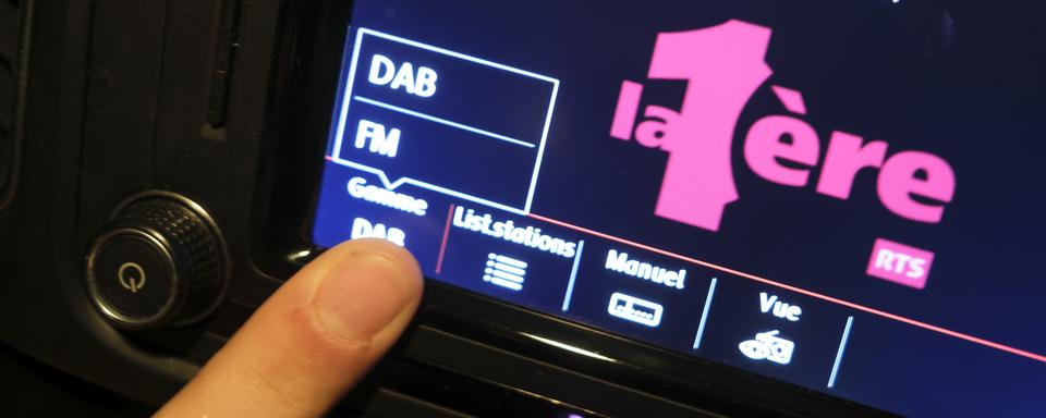 Une personne commute un autoradio de la FM au DAB. Le 31 décembre 2024, les fréquences FM des radios de la SSR seront supprimées. Celles-ci ne pourront alors plus être captées que via DAB+ et Internet. [Keystone - Laurent Gillieron]