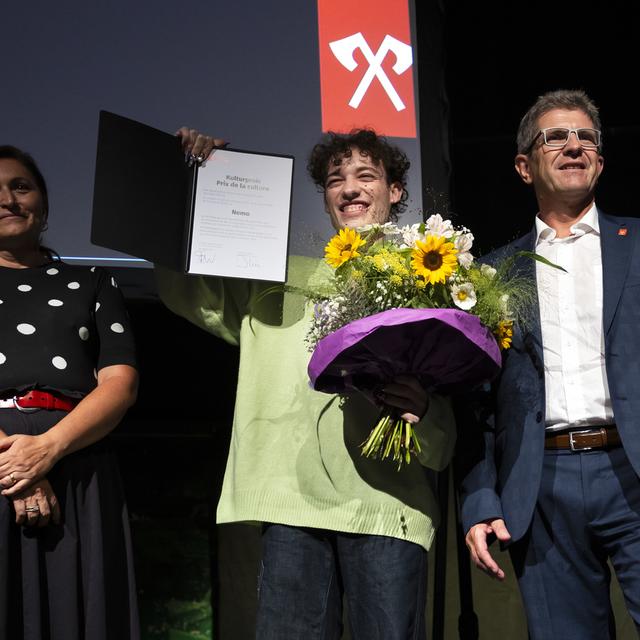 L'artiste suisse Nemo pose avec le président de la ville Erich Fehr et la conseillère municipale Glenda Gonzalez Bassi lors de la remise du Prix de la culture de la ville de Bienne, le mardi 3 septembre 2024. [Keystone - Peter Klaunzer]