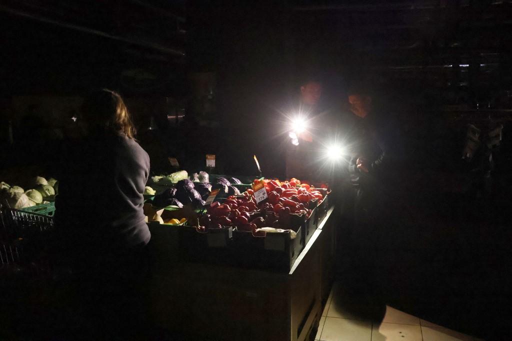 Des clients utilisent des flashs d'appareil photo pour éclairer des légumes dans un supermarché pendant une panne d'électricité à Kiev, en Ukraine, le 27 novembre 2024. [NurPhoto via AFP - OLEKSANDR KLYMENKO]