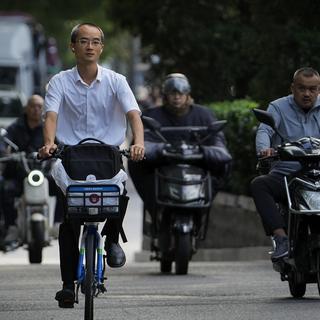 A man rides along motorists as they head to work during the morning rush hour in Beijing, Friday, Sept. 13, 2024. [Keystone/AP Photo - Andy Wong]