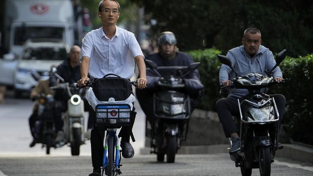 A man rides along motorists as they head to work during the morning rush hour in Beijing, Friday, Sept. 13, 2024. [Keystone/AP Photo - Andy Wong]