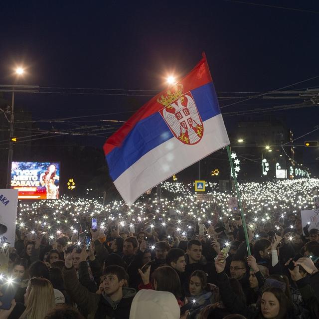 Un drapeau serbe flottant au milieu des manifestations populaires contre le président Aleksander Vucic et son gouvernement. Belgrade, Serbie, le 22 décembre 2024. [AP Photo/Keystone - Marko Drobnjakovic]