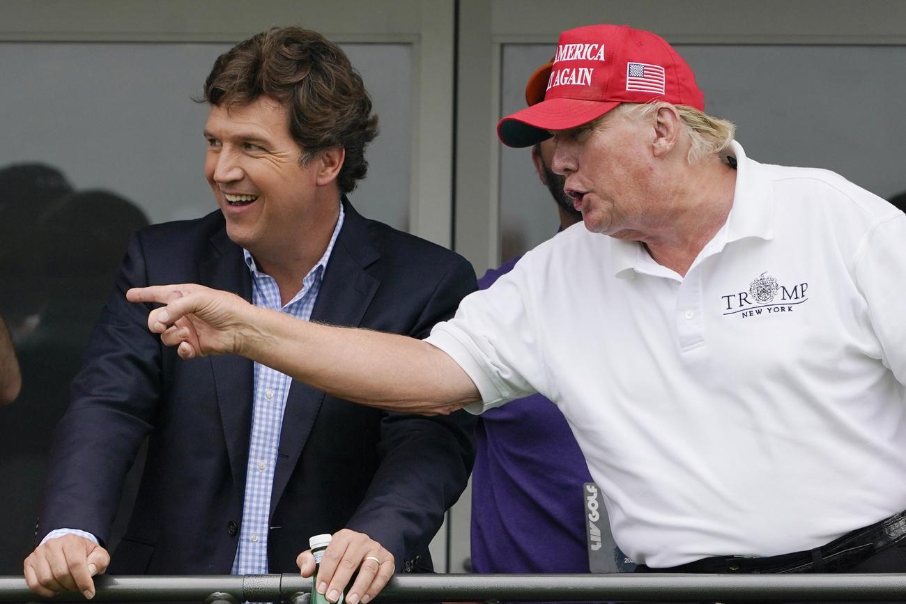 Le présentateur Tucker Carlson, ici en juillet 2022 avec Donald Trump durant un tournoi de golf. [KEYSTONE - SETH WENIG]