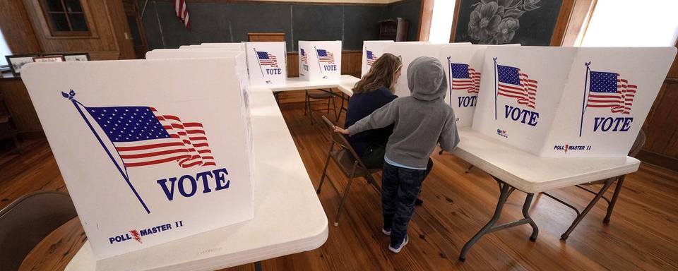 Une femme, accompagnée de son fils, dans un bureau de vote. 5 novembre 2024. [AP Photo/Keystone - Charlie Riedel]