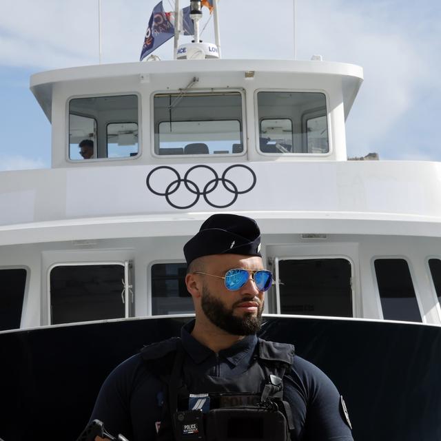 Un policier qui surveille l'arrivée la flamme olympique. [Keystone/EPA - Guillaume Horcajuelo]