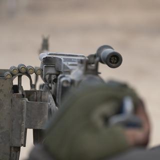 Un soldat israélien tirant avec une mitraillette à Gaza. [Keystone/AP Photo - Victor R. Caivano]