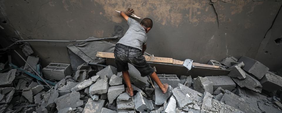 Un enfant palestinien inspecte les débris d'une mosquée, détruite par un bombardement aérien, au centre de la bande de Gaza. [EPA/Keystone - Mohammed Saber]