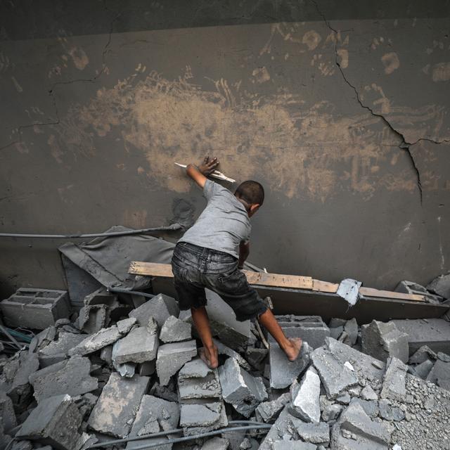 Un enfant palestinien inspecte les débris d'une mosquée, détruite par un bombardement aérien, au centre de la bande de Gaza. [EPA/Keystone - Mohammed Saber]