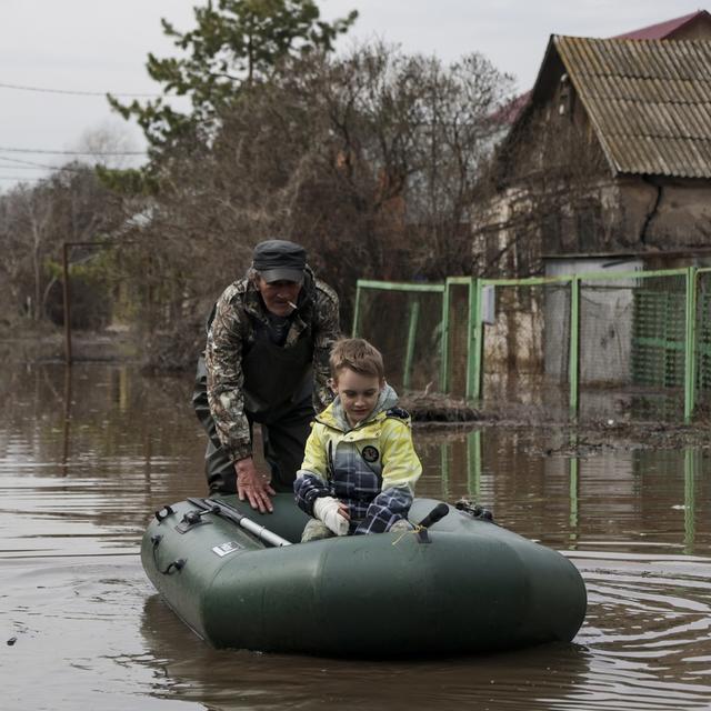 Un homme aidant un garçon sur un bateau dans une région inondée en Russie. [Keystone/AP Photo - DR]