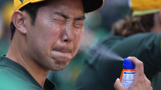 Un joueur de baseball se met de la crème solaire sur le visage en plein match. [Keystone - Ross D. Franklin]
