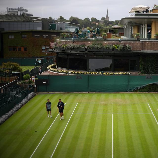 Les employés du court de tennis anglais de Wimbledon en train de préparer un terrain. [Keystone/EPA - Adam Vaughan]