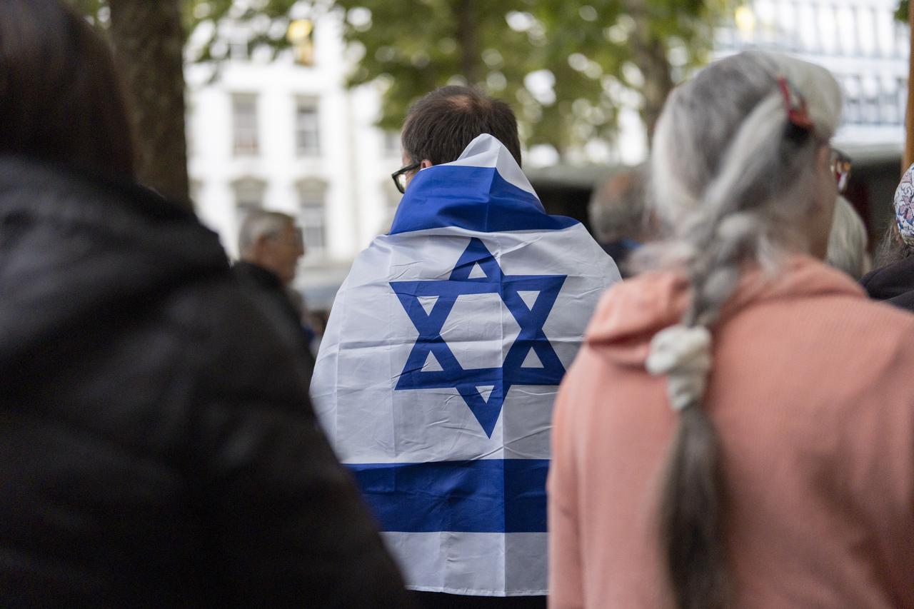 Un homme porte un drapeau israélien sur son dos à Zurich, le 7 octobre 2024, jour de commémoration de l'attaque du Hamas en Israël. [KEYSTONE - TIL BUERGY]