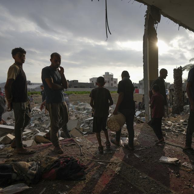 Des Palestiniens devant le bâtiment d'une mosquée détruite, le 6 octobre 2024. [Keystone - AP Photo/Abdel Kareem Hana]