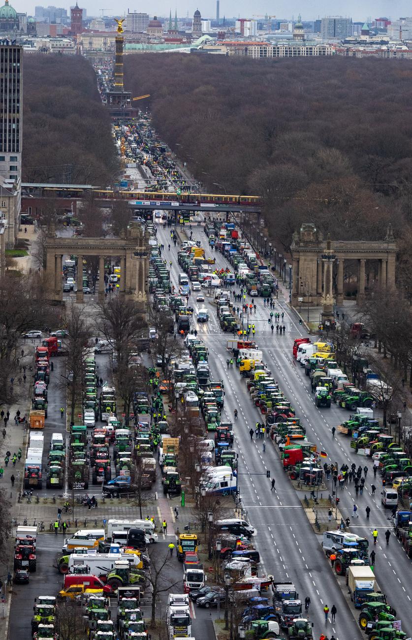 De nombreux tracteurs, camions et voitures sont stationnés lundi matin dans la rue du 17 juin, avec la colonne de la Victoire en toile de fond, le 15 janvier 2024. [KEYSTONE - MONIKA SKOLIMOWSKA]