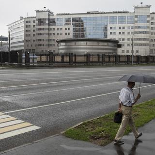 Un homme portant un parapluie passe se balade près du bâtiment du service de renseignement russe à Moscou. [Keystone/AP Photo - Pavel Golovkin]