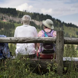 Des randonneurs se reposent sur un banc et profitent du panorama en haut du Rigi. [Keystone - Gaëtan Bally]