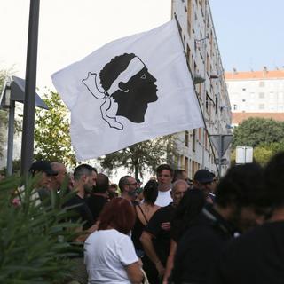 Des centaines de personnes se rassemblent avec un drapeau corse pour protester contre les trafiquants de drogue le 17 août 2023 à Ajaccio, en Corse. [AFP - Pascal POCHARD-CASABIANCA]