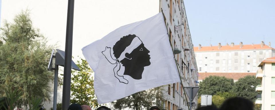 Des centaines de personnes se rassemblent avec un drapeau corse pour protester contre les trafiquants de drogue le 17 août 2023 à Ajaccio, en Corse. [AFP - Pascal POCHARD-CASABIANCA]