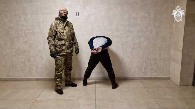 Un enquêteur russe escorte un suspect après la fusillade dans une salle de concert de Moscou. [Keystone]
