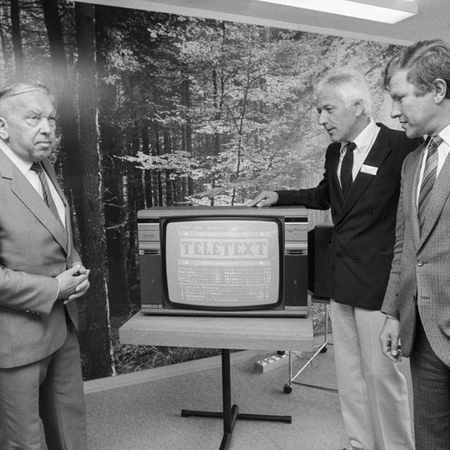 De gauche à droite, Leo Schürmann, directeur général de la SSR, Hugo Marty, directeur du télétexte, et Hermann Fehr, maire de Bienne, lors de la conférence de lancement du télétexte en 1984. [Keystone]