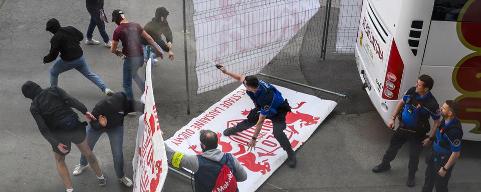 Des supporters ultras de Bellinzone affrontent la police lausannoise près du car de l'équipe tessinoise après une rencontre de football de Challenge League entre FC Stade Lausanne Ouchy et AC Bellinzona le 27 mai 2023 au stade olympique de la Pontaise à Lausanne. [Keystone - Jean-Christophe Bott]