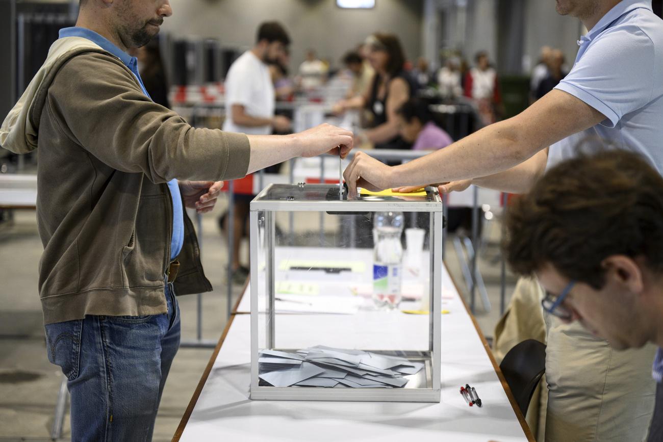 Des Françaises et Français glissent leur bulletin dans l'urne au bureau de vote de Beaulieu à Lausanne. [KEYSTONE - LAURENT GILLIERON]
