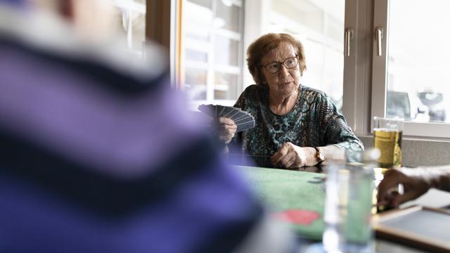 Une femme âgée jouant aux cartes avec d'autres seniors. [Keystone - Gaetan Bally]