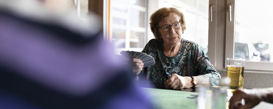 Une femme âgée jouant aux cartes avec d'autres seniors. [Keystone - Gaetan Bally]