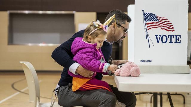 Un électeur et sa fille dans un bureau de vote du Michigan. [KEYSTONE - KENDALL WARNER]