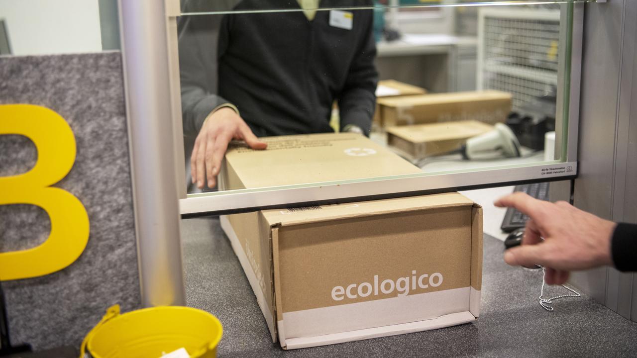 Un client dépose des colis au guichet dans un office de La Poste. [Keystone - Christian Beutler]