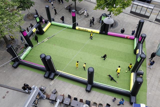 Des enfants jouent au football sur un terrain mobile installé sur la place de la Navigation le 24 avril 2024 à Genève. Johan Djourou, ancien international suisse, est à l'origine de ce projet nommé "Mondialito". [KEYSTONE - SALVATORE DI NOLFI]