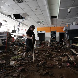 Des femmes nettoient un supermarché à Paiporta, proche de Valence, détruit après les inondations meurtrières des jours passés. [EPA/Keystone - Biel Alino]