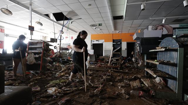 Des femmes nettoient un supermarché à Paiporta, proche de Valence, détruit après les inondations meurtrières des jours passés. [EPA/Keystone - Biel Alino]