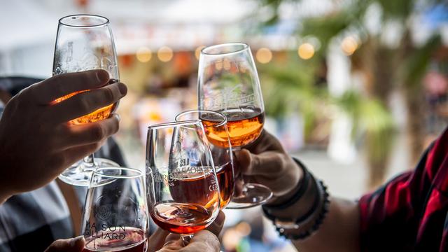 Des personnes dégustant des verres de vin lors de l'édition 2021 de la Foire du Valais. [keystone - Jean-Christophe Bott]