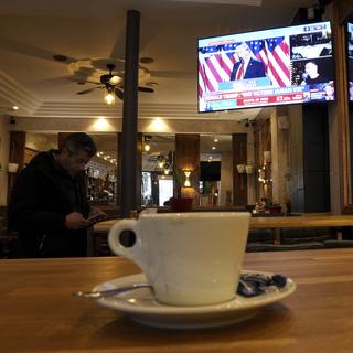 Un homme regarde son téléphone dans un café parisien. [Keystone/AP Photo - Aurelien Morissard]