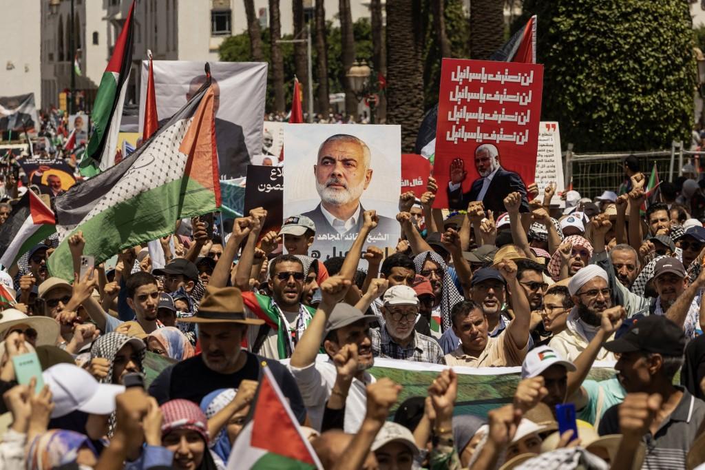 Des manifestants brandissent des pancartes et des drapeaux de la Palestine lors d'un rassemblement à Rabat, au Maroc, pour protester contre l'assassinat du chef du Hamas Ismaïl Haniyeh. [AFP - FADEL SENNA]