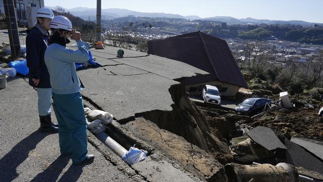 Des personnes observent les dégâts du séisme du 1er janvier 2024 à Kanazawa au Japon. [Keystone/EPA - Franck Robichon]