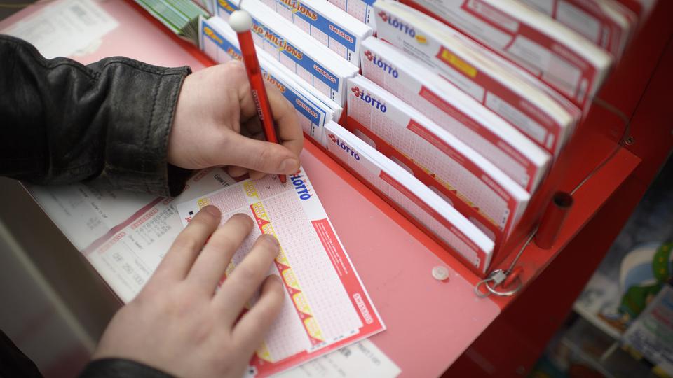 Un homme remplit un billet de loterie de Swisslos en 2016. [KEYSTONE - GIAN EHRENZELLER]