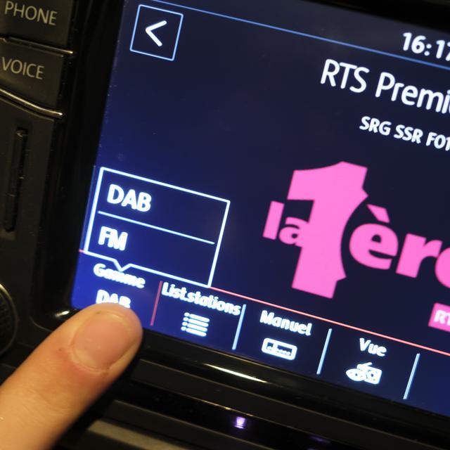 Une personne commute un autoradio de la FM au DAB. Le 31 décembre 2024, les fréquences FM des radios de la SSR seront supprimées. Celles-ci ne pourront alors plus être captées que via DAB+ et Internet. [Keystone - Laurent Gillieron]