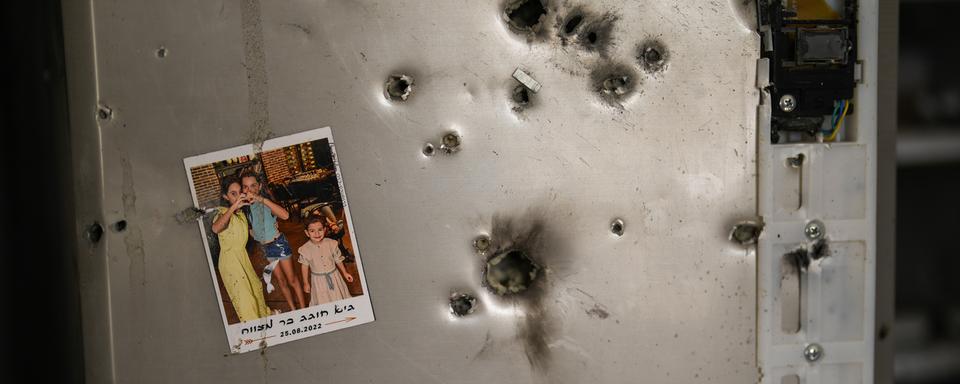 Une photo est accrochée à un réfrigérateur à côté d'impacts de balles dans une maison du kibboutz Kissufim, dans le sud d'Israël, le samedi 21 octobre 2023. Le kibboutz a été envahi par les militants du Hamas de la bande de Gaza voisine le 7 octobre, lorsqu'ils ont tué et capturé de nombreux Israéliens. Human Rights Watch a publié un rapport mercredi 17 juillet 2024, affirmant que les groupes armés dirigés par le Hamas ont commis de nombreux crimes de guerre lors de l'attaque du 7 octobre sur le sud d'Israël, qui a précipité la guerre en cours dans la bande de Gaza. [AP Photo/ Keystone - Francisco Seco]