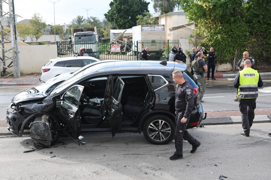 Le personnel israélien d'urgence et de sécurité se tient à côté d'une voiture endommagée à la suite d'une attaque à la voiture bélier dans la ville centrale de Raanana, le 15 janvier 2024. [AFP - JACK GUEZ]