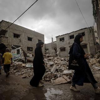 Palestinians walk past a destroyed house following an Israeli air strike in Al Nusairat refugee camp, central Gaza Strip, 01 October 2024. More than 41,000 Palestinians and over 1,400 Israelis have been killed, according to the Palestinian Health Ministry and the Israel Defense Forces (IDF), since Hamas militants launched an attack against Israel from the Gaza Strip on 07 October 2023, and the Israeli operations in Gaza and the West Bank which followed it. [EPA/Keystone - MOHAMMED SABER]