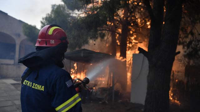 Un pompier grec se bat pour éteindre une maison en flamme au nord d'Athènes. La Grèce est touchée depuis plusieurs jours par des mégas incendies. Le 12 août 2024. [AP Photo/KEYSTONE - Michael Varaklas]