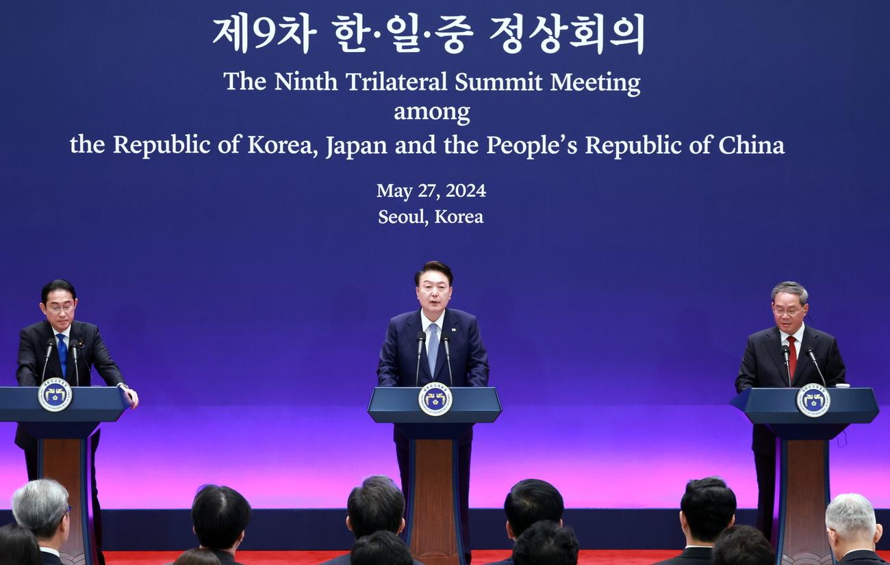 Le président sud-coréen Yoon Suk Yeol s'exprime entouré des Premiers ministres japonais Fumio Kishida (gauche) et chinois Li Qiang (droite). [KEYSTONE - YONHAP / POOL]