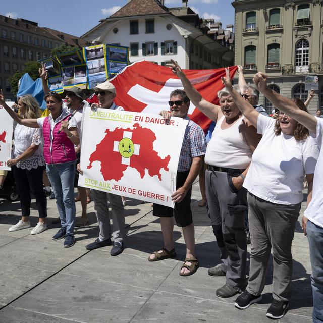 Des manifestants avec des pancartes "la neutralité en danger: stop aux jeux de guerre" sur la place fédérale à Berne le 15 juin 2023. [Keystone - Anthony Anex]