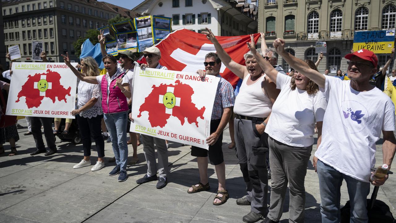 Des manifestants avec des pancartes "la neutralité en danger: stop aux jeux de guerre" sur la place fédérale à Berne le 15 juin 2023. [Keystone - Anthony Anex]