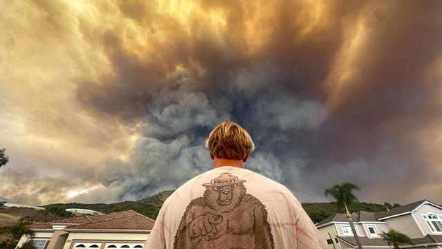 Un homme regarde la fumée liée à l'Airport Fire s'élever derrière Meander Lane, à Trabuco Canyon, en Californie. [Keystone]